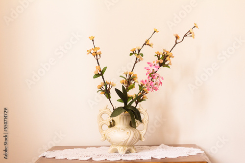 Schilderij op canvas white ceramic vase with artificial flowers on a knitted napkin on a wooden table
