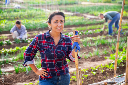 Portrait of positive woman standing with shovel in homestead outdoors