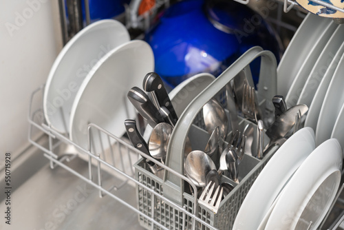 Woman with full dishwasher machine for housework in kitchen