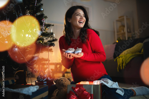 Beautiful young pregnant woman opening Christmas presents