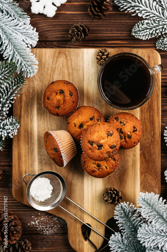 
muffins with chocolate on a wooden stand, powdered sugar, cones, Christmas tree branches nearby