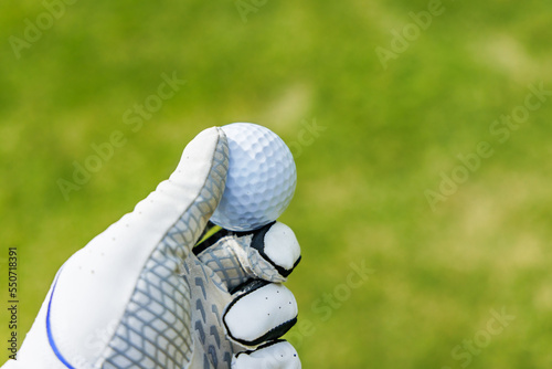 芝生が綺麗なゴルフ場と手に持ったゴルフボール