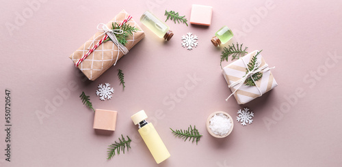 Frame made of Christmas decor with natural cosmetics and gifts on pink background