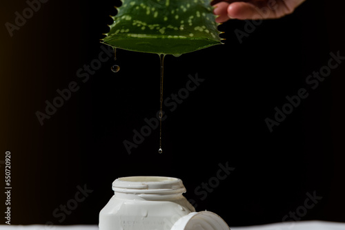 person draining the juice of an Aloe Vera leaf over a plastic container