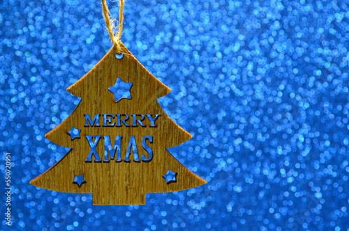 Merry Christmas or winter holidays concept.Wooden christmas tree on gllitter blue background for design with copy space.Selective focus. photo