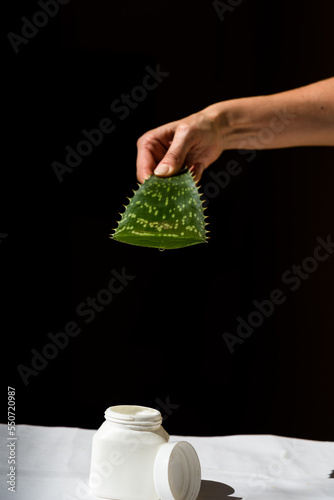 person draining the juice of an Aloe Vera leaf over a plastic container