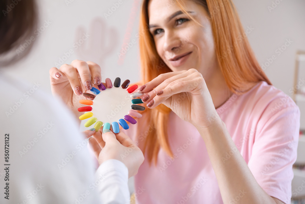 Transgender manicure master with nail polish tips and client in salon, closeup Transgender manicure master with nail polish tips and client in salon, closeup
