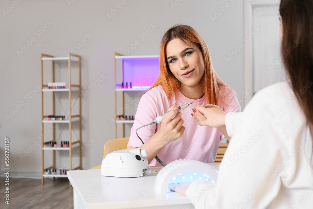 Transgender manicure master working with client at table in nail salon Transgender manicure master working with client at table in nail salon