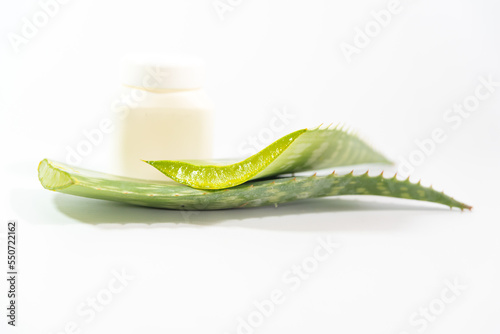 fresh Aloe Vera leaves next to plastic container on a table