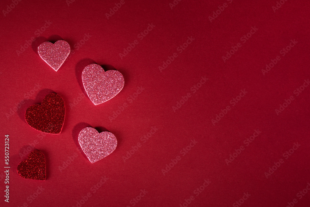 Obraz premium Valentine's day concept banner with sparkling glitter hearts against abstract red background and the bokeh of garland with space for text.