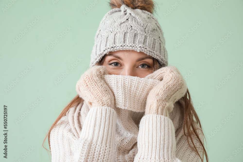 Young woman in warm hat and scarf on green background Young woman in warm hat and scarf on green background