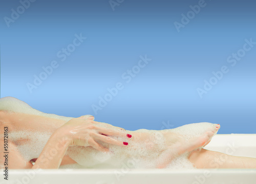 young woman hands and feet covered with foam inside white bath 