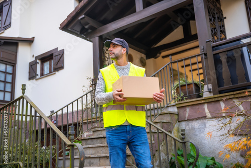 A young delivery man in a protective uniform at the delivery of the online order, with a box