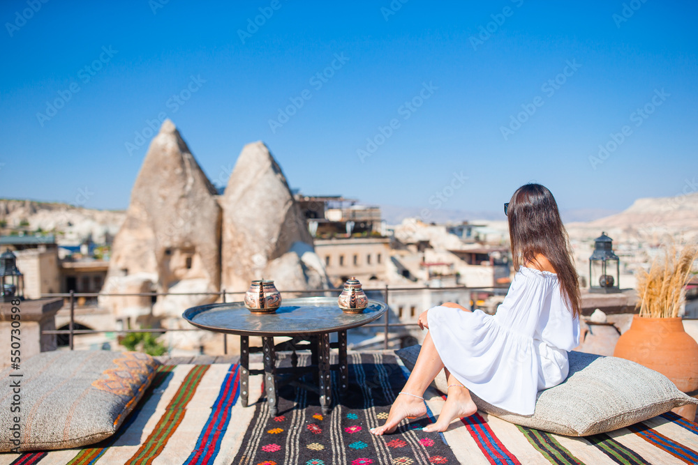 Happy young woman during vacation watching hot air balloons in Cappadocia, Turkey