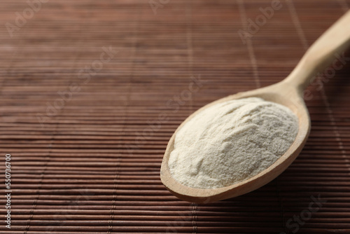 Spoon of agar-agar powder on bamboo mat, closeup. Space for text