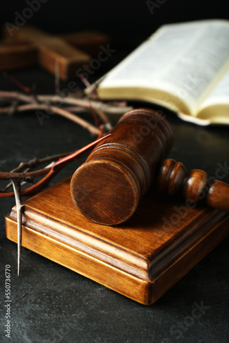 Wooden judge gavel and crown of thorns on black table, closeup