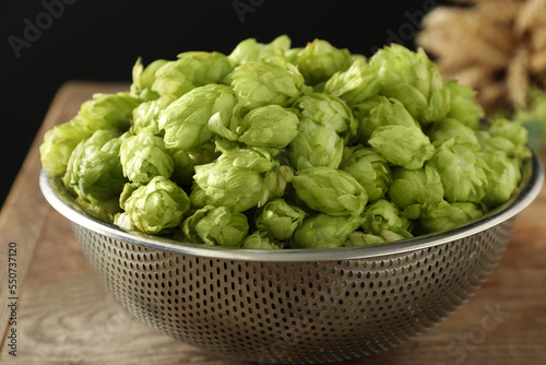 Fresh green hops in sieve on table, closeup