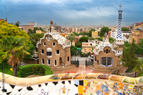 Daytime photo of Park Güell in Barcelona, Spain with the Casa del Guarda gatehouses in the foreground and the Barcelona cityscape in the background.