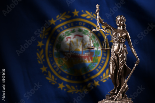 New Hampshire US state flag with statue of lady justice and judicial scales in dark room. Concept of judgement and punishment, background for jury topics photo