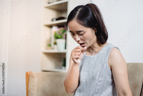 Sick woman coughing or wheezing sitting on a desk in the living room at home