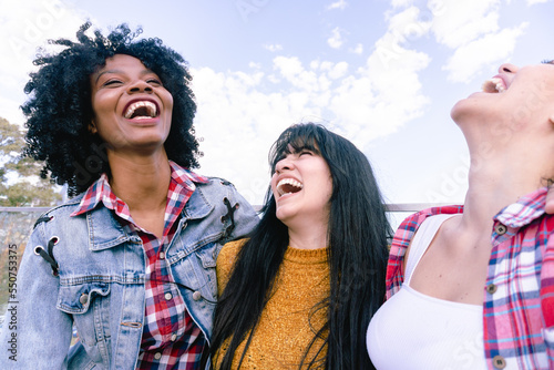 Haitian woman laughing with her two Latina friends in a park