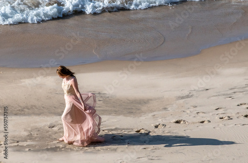 Pretty teen in a  flowing dress walks along the beach on the shores of lake Michigan