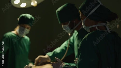 Female doctor walk into Hospital Operating Room. Diverse Team, Multi ethnic of professional surgeons and nurses suture wound having discussion for successful surgery operation on intensive care