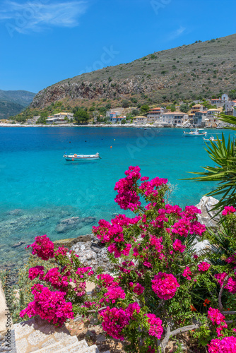 view of Limeni village with the famous stone buildings, a blooming bougainvillea, and turquoise waters a as a background in Mani, South Peloponnese , Greece.