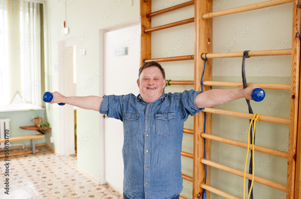 A man with Down syndrome does sports, does a warm-up in the gym A man with Down syndrome does sports, does a warm-up in the gym
