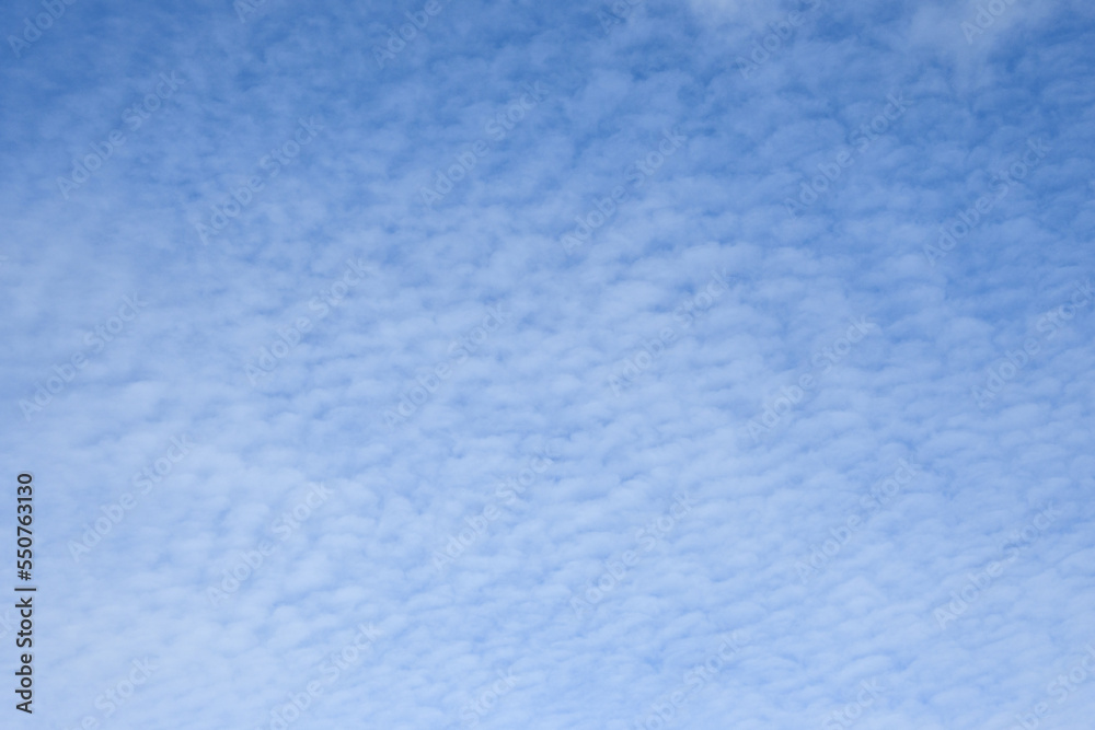 Sunny blue sky with a cover of light textured clouds, as a nature background
