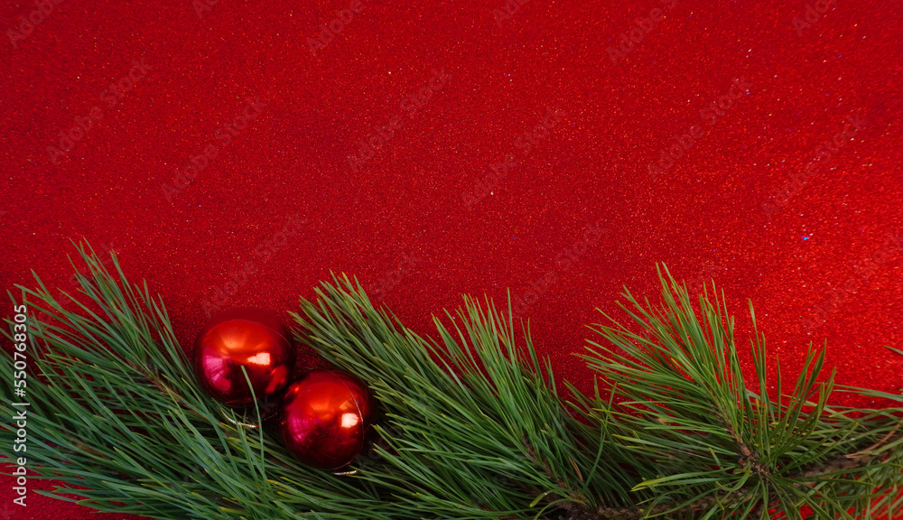Red Christmas background with Christmas tree branch and Christmas balls and toys
