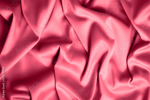 Textured background of red silk or satin. Color of the Year 2023