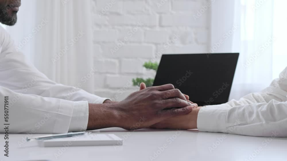 African American doctor holding the hand of the patient. Kind ethnic professional doctor expresses sympathy, encourages comforting infertile patient when visiting a doctor, close-up.