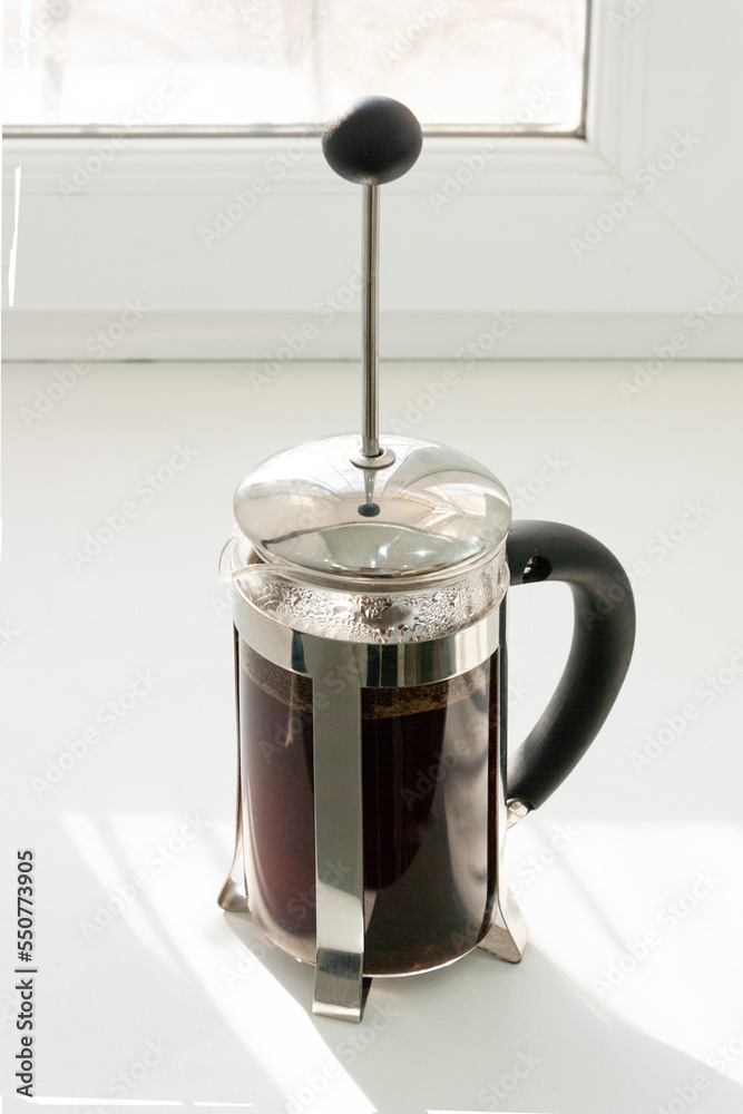 coffee is brewed in a french press, the shadow from the window coffee is brewed in a french press, the shadow from the window