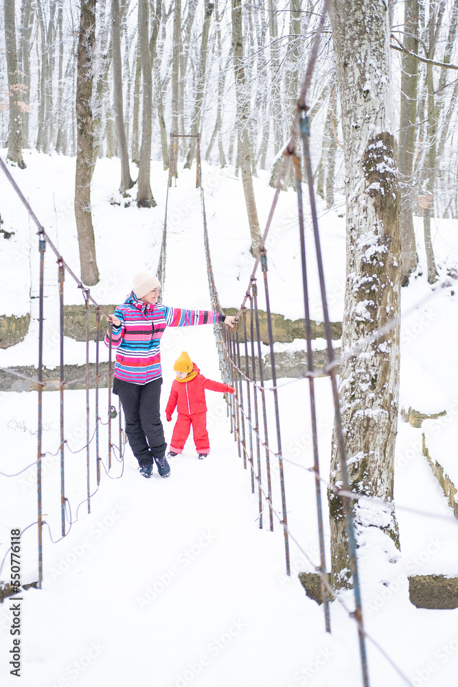 Mother and daughter in colorful clothes having fun on winter walk in nature Mother and daughter in colorful clothes having fun on winter walk in nature