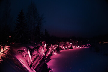 Foto auf Acrylglas Pantone 2023 Viva Magenta Beautiful panoramic view of night park with colorful lights Viva Magenta on winter forest and rocks, Ruskeala, Karelia, Russia. Trendy creative design in color of 2023. High quality photo  © lara-sh