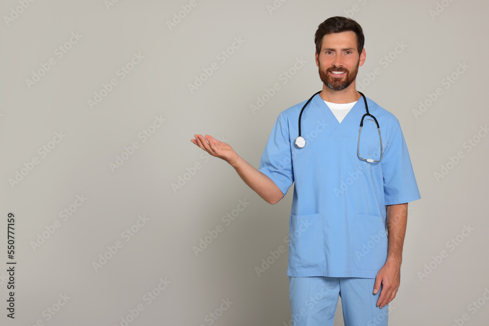 Happy doctor with stethoscope on light grey background. Space for text Happy doctor with stethoscope on light grey background. Space for text