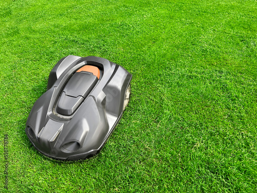 Obraz na plátně Modern robot lawn mower on green grass in garden