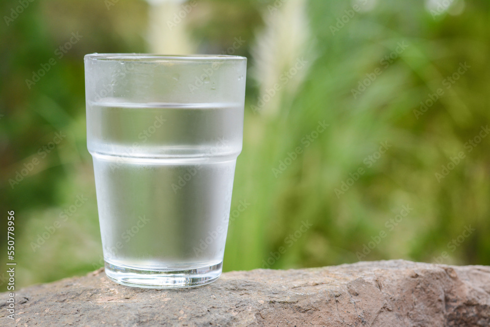 Full glass of water on stone outdoors, closeup. Space for text Full glass of water on stone outdoors, closeup. Space for text