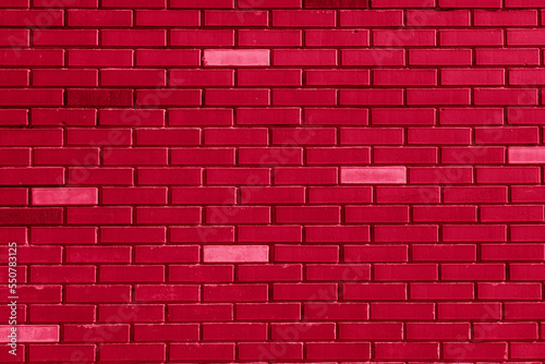 Red brick wall texture with light blocks background toned in trendy Viva Magenta color of Year 2023