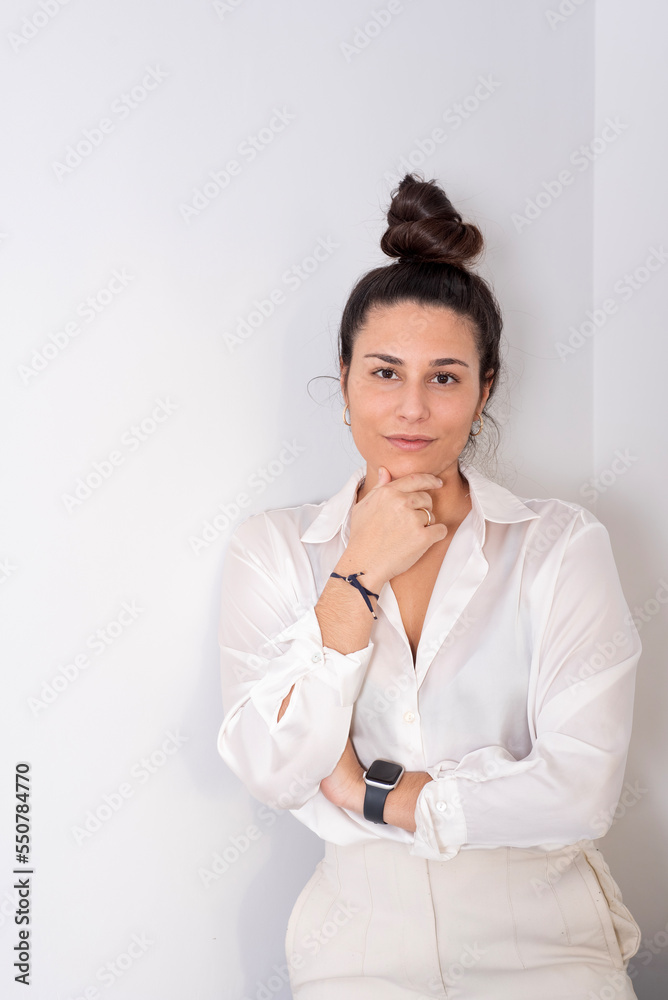 portrait on white wall of an empowered young woman in white executive clothes portrait on white wall of an empowered young woman in white executive clothes