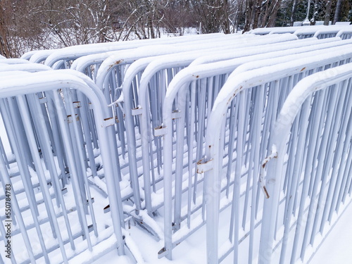 Metal fencing for mass events in winter in the park under the snow. Preparing a concert on a frosty day.