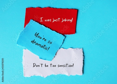 On blue background, torn paper with handwriting I WAS JUST JOKING, YOU'RE SO DRAMATIC and DON'T BE SO SENSITIVE, gaslighting verbal abuse use to manipulate and pin whole blame to victim photo