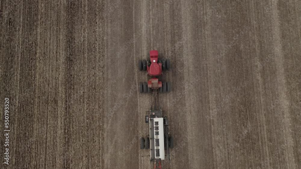 Tractor and seeder plants fertile field, Saskatchewan, Canada. Bird's eye view. Tractor and seeder plants fertile field, Saskatchewan, Canada. Bird's eye view.
