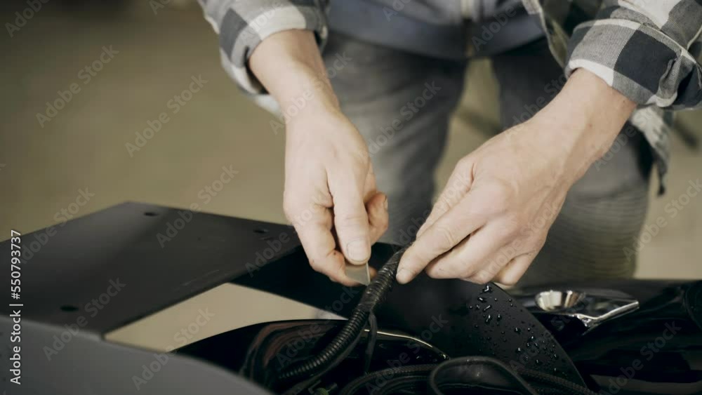 A mechanic cuts the insulation of the electrical cable of an electrical equipment in a motorcycle. Close-up. Transport concept