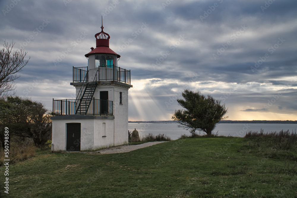 Lighthouse, Spodsbjerg Fyr in Huntsted on the coast of Denmark. Sun rays shining