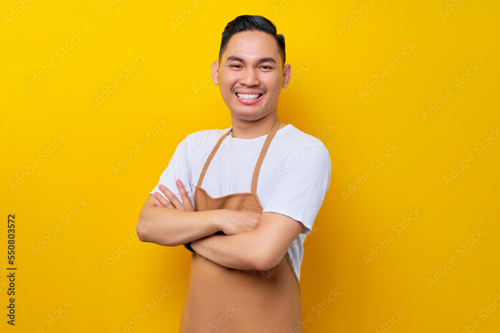 © Bangun Stock Photo - Optimistic young Asian man 20s barista employee wearing brown apron working in coffee shop, standing with crossed arms, looking on camera with toothy smile on yellow background. Small business startup © Bangun Stock Photo - Optimistic young Asian man 20s barista employee wearing brown apron working in coffee shop, standing with crossed arms, looking on camera with toothy smile on yellow background. Small business startup