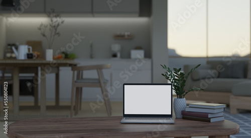 Home workspace with laptop on coffee table over blurred background of kitchen and dining room © bongkarn