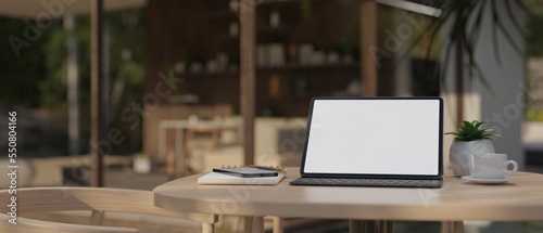 Portable tablet with wireless keyboard on wood table over blurred of beautiful coffee shop