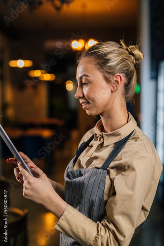 Profile of a young waitress using a tablet